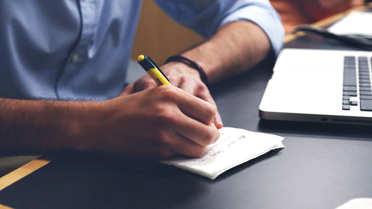 Close up of a man's hand writing on a notepad